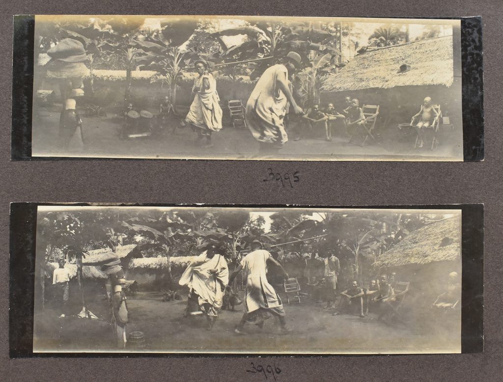 Wide photos taken by Northcote Thomas or one of his helpers, labeled ‘Chief dancing’ in Thomas’s photo record. The Ngene figure and other items from the official photo can be seen in the background. You can also see children sitting on Thomas’s camp chairs, watching the event, and one of his assistants on the left side of the bottom photo. (NWT 3995 & 3996)