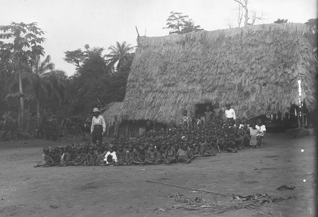 Photograph of Igbo villagers in a rural settlement with thatched-roof houses, captured by missionary-anthropologist G. T. Basden around 1910.
