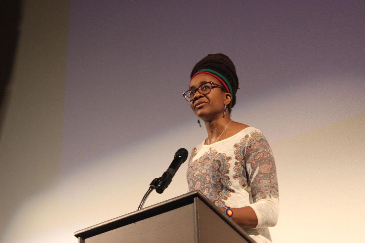 Nigerian-American author Nnedi Okorafor speaking at a podium during a book reading.