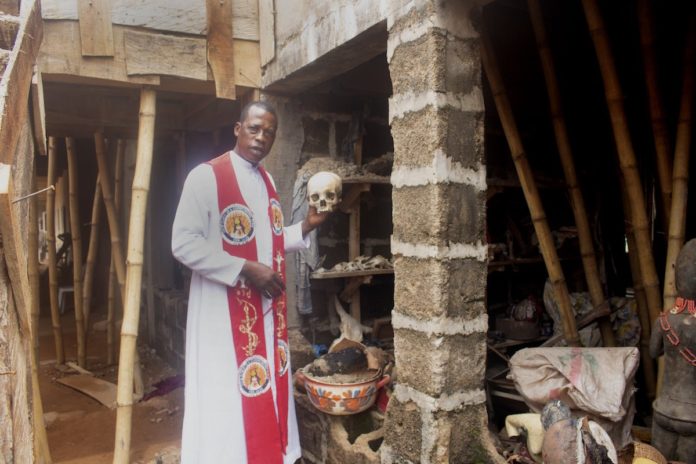 Father Paul Obayi holds a human skull recovered from a shrine during an exorcism, in this photo taken on April 19, 2022, in Nsukka, Nigeria. A designated exorcist, Father Obayi preserves traditional religious artefacts in a museum to safeguard local cultural heritage. — (CNS photo/Valentine Iwenwanne)