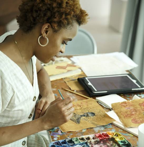 Nigerian artist painting watercolor inspired by Igbo spirituality.