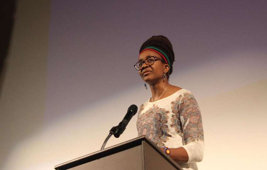 Nigerian-American author Nnedi Okorafor speaking at a podium during a book reading.